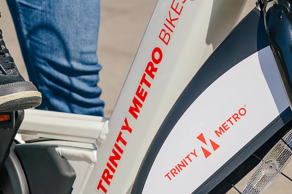 Close-up of person wearing Nike tennis shoe on Trinity Metro bike share e-bike.